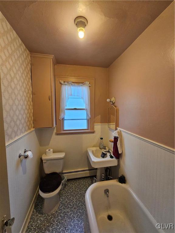 bathroom featuring a washtub, sink, a baseboard radiator, a textured ceiling, and toilet