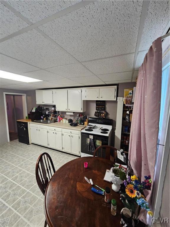 kitchen with a paneled ceiling, white cabinetry, sink, and white electric range oven