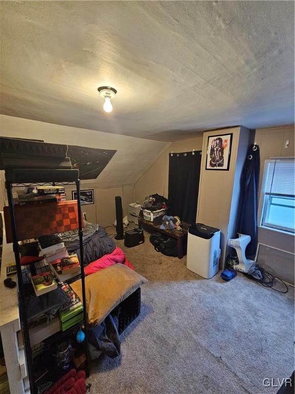 bedroom with carpet, a textured ceiling, and lofted ceiling