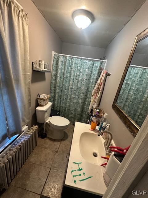 bathroom with tile patterned flooring, radiator heating unit, toilet, and sink