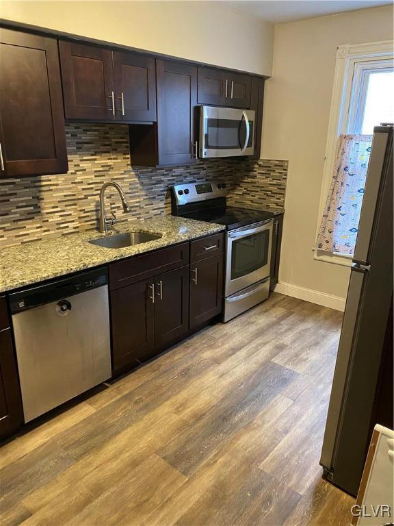 kitchen featuring tasteful backsplash, dark brown cabinets, stainless steel appliances, sink, and light hardwood / wood-style flooring