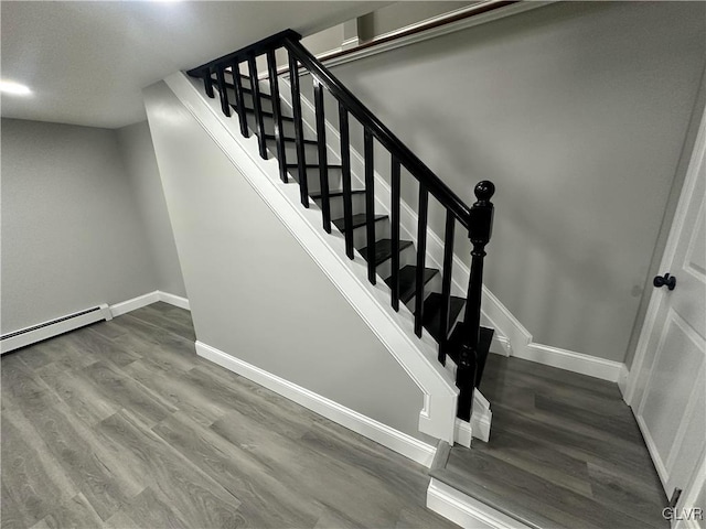 staircase with hardwood / wood-style floors and a baseboard heating unit