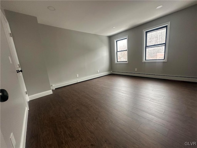 empty room featuring dark hardwood / wood-style floors and a baseboard heating unit