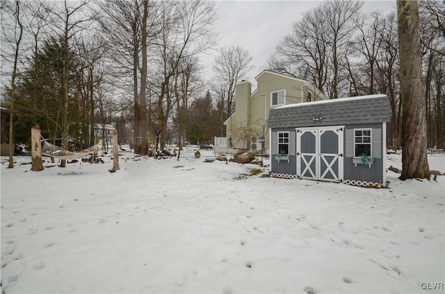 snowy yard with a storage shed