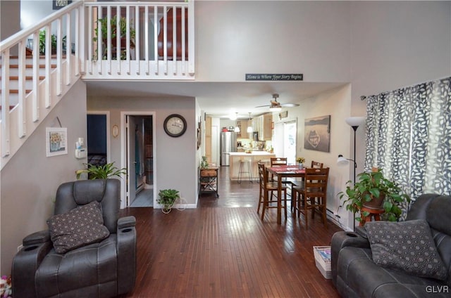 living room with hardwood / wood-style floors, ceiling fan, and a high ceiling