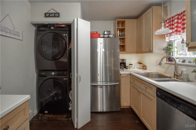 kitchen with appliances with stainless steel finishes, stacked washing maching and dryer, dark wood-type flooring, sink, and decorative light fixtures