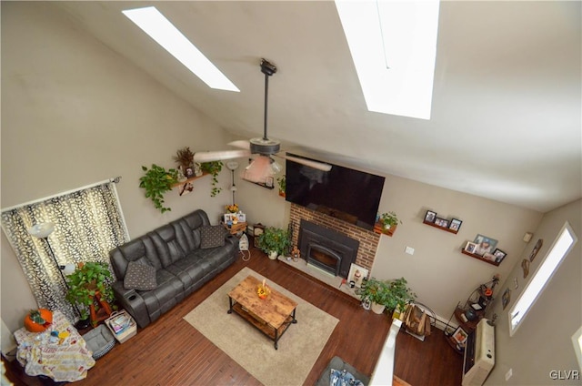 living room with hardwood / wood-style flooring, ceiling fan, and vaulted ceiling with skylight