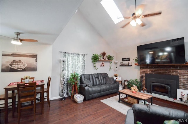 living area featuring a skylight, a fireplace, ceiling fan, wood finished floors, and high vaulted ceiling