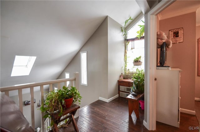 interior space featuring a wealth of natural light, vaulted ceiling with skylight, baseboards, and hardwood / wood-style floors