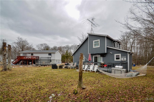 back of property featuring a lawn and a wooden deck