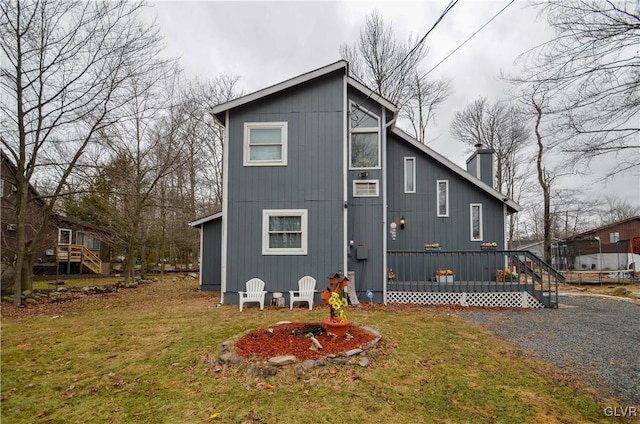 rear view of house with driveway, a yard, and a chimney