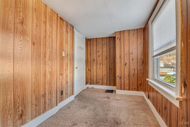 carpeted empty room featuring wooden walls