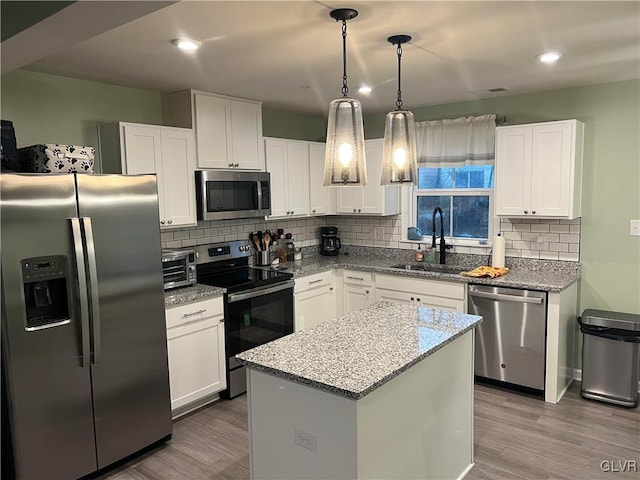 kitchen with sink, a kitchen island, light hardwood / wood-style floors, white cabinetry, and stainless steel appliances