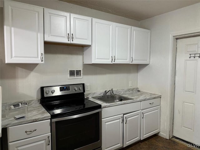 kitchen featuring stainless steel range with electric stovetop, white cabinetry, and sink