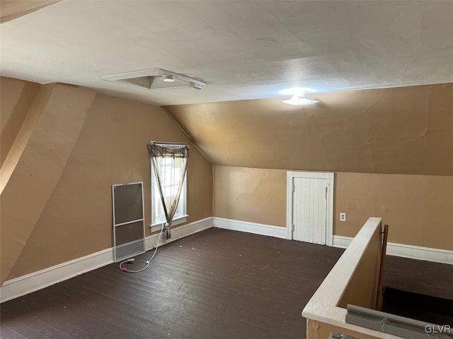 additional living space featuring dark wood-type flooring and vaulted ceiling