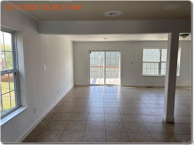 empty room with dark tile patterned flooring and a wealth of natural light