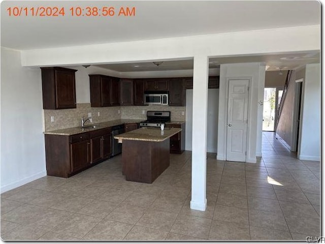 kitchen with dark brown cabinetry, a center island, tasteful backsplash, light tile patterned floors, and appliances with stainless steel finishes