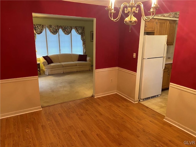 unfurnished dining area with a chandelier and light hardwood / wood-style floors