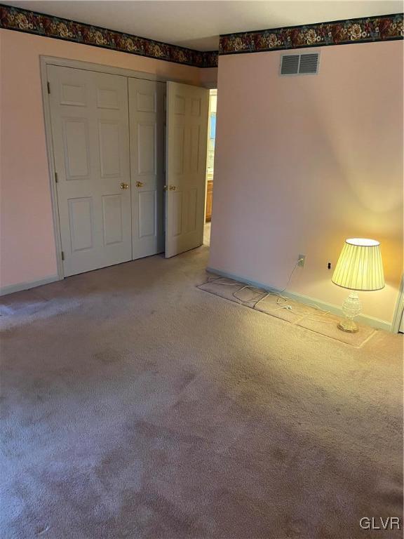 unfurnished bedroom with a closet and light colored carpet