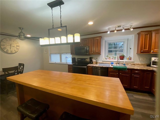 kitchen with black appliances, sink, hanging light fixtures, dark hardwood / wood-style flooring, and butcher block counters