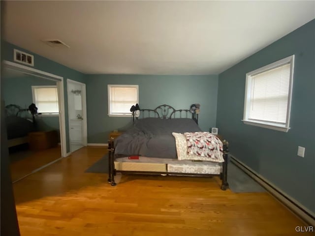 bedroom featuring wood-type flooring and a baseboard heating unit