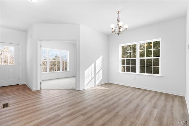 unfurnished dining area with light hardwood / wood-style flooring, a wealth of natural light, and a notable chandelier