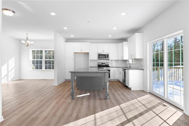 kitchen with white cabinets, appliances with stainless steel finishes, a kitchen island, and sink