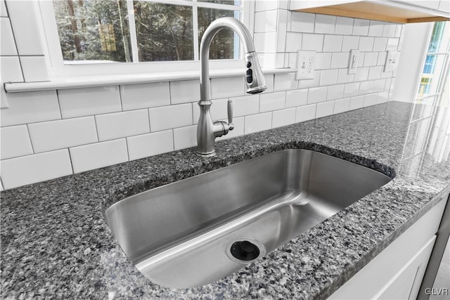 details with white cabinets, sink, dark stone counters, and tasteful backsplash