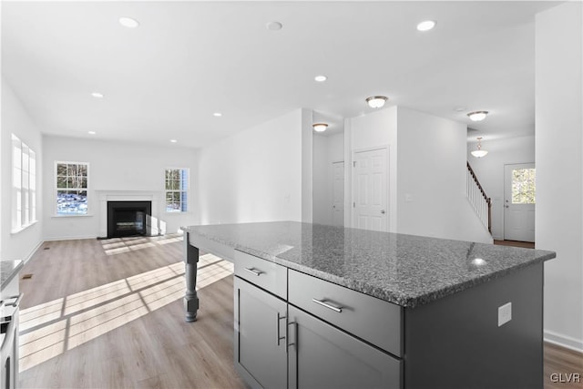 kitchen featuring a kitchen island, dark stone counters, and light hardwood / wood-style flooring