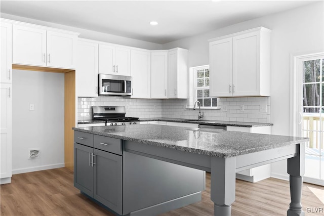 kitchen featuring white cabinets, dark stone countertops, hardwood / wood-style floors, and appliances with stainless steel finishes