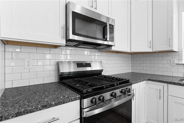 kitchen with backsplash, dark stone countertops, white cabinetry, and stainless steel appliances