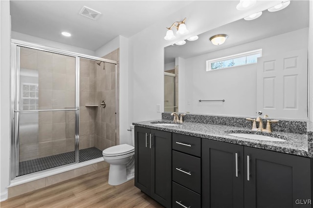 bathroom with hardwood / wood-style floors, vanity, a shower with door, and toilet