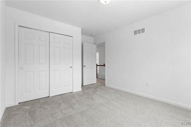 unfurnished bedroom with a closet and light colored carpet