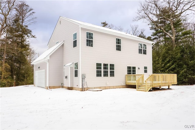 snow covered house featuring a deck and a garage