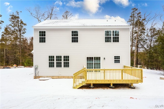 snow covered back of property with a wooden deck