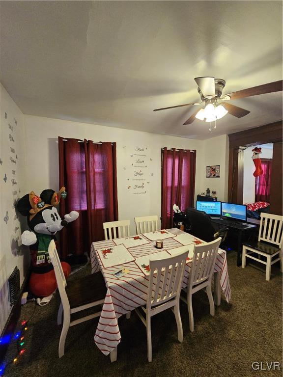 dining space featuring ceiling fan and dark carpet