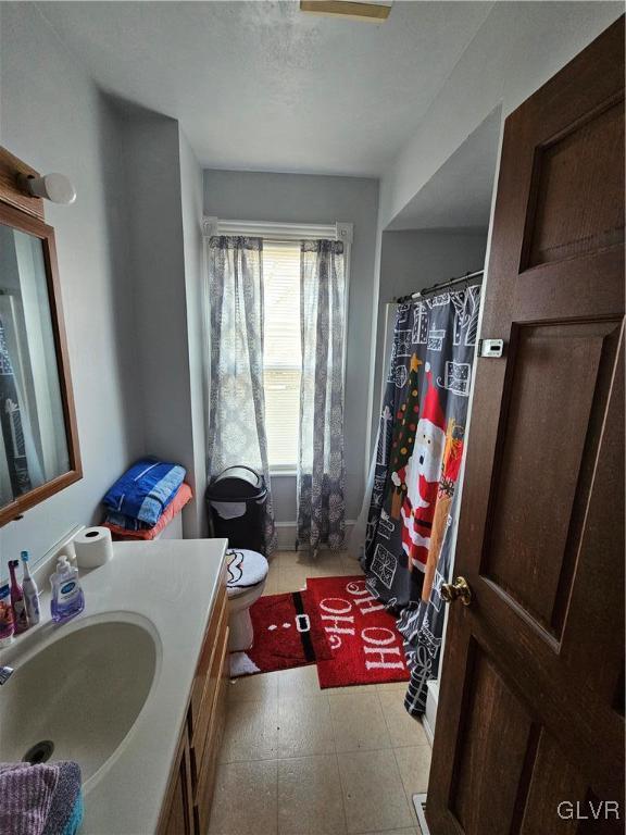 bathroom with a shower with curtain, vanity, a textured ceiling, and toilet