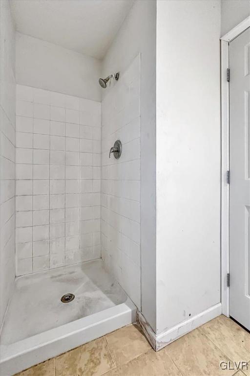 bathroom with tiled shower and tile patterned flooring