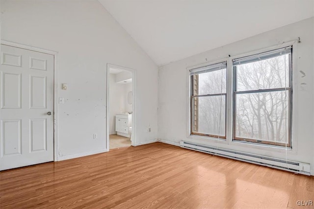 empty room with baseboard heating, light hardwood / wood-style floors, and lofted ceiling