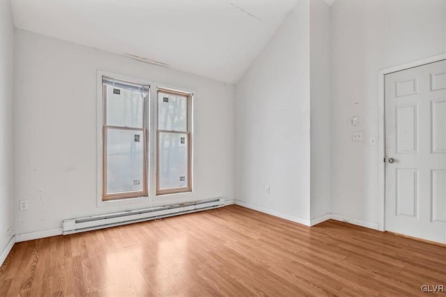 unfurnished room featuring light wood-type flooring, vaulted ceiling, and a baseboard heating unit