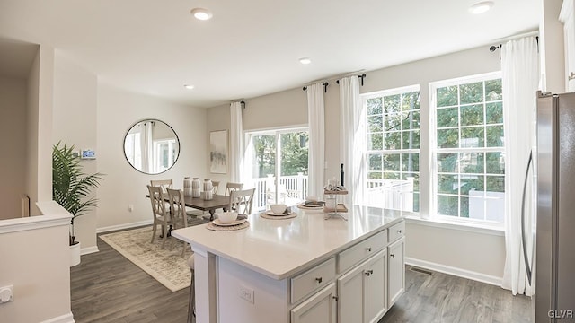 kitchen featuring a center island, dark hardwood / wood-style floors, stainless steel fridge, and white cabinets