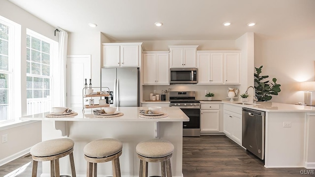 kitchen with white cabinets, a kitchen breakfast bar, sink, dark hardwood / wood-style flooring, and stainless steel appliances