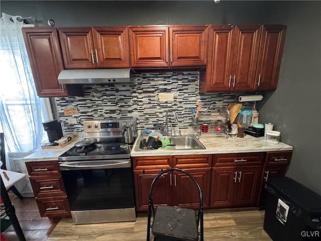 kitchen with stainless steel electric stove, backsplash, sink, and light wood-type flooring