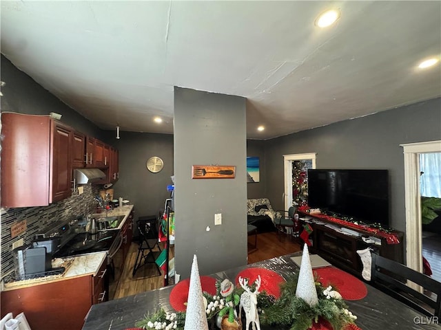 interior space featuring backsplash, ventilation hood, black range with electric stovetop, sink, and dark hardwood / wood-style floors