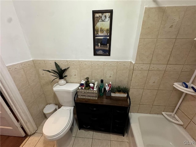 bathroom with tile patterned flooring, a bath, toilet, and tile walls