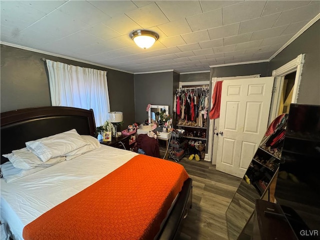 bedroom featuring wood-type flooring, crown molding, and a closet