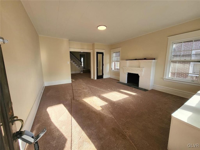 unfurnished living room featuring a wealth of natural light and dark colored carpet