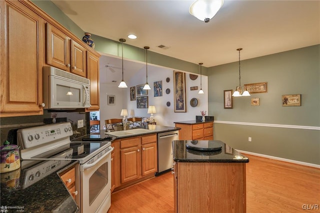 kitchen with a center island, white appliances, sink, light hardwood / wood-style flooring, and decorative light fixtures