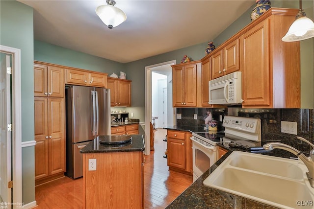 kitchen featuring white appliances, sink, pendant lighting, light hardwood / wood-style flooring, and a center island