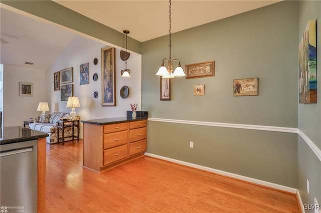 kitchen with pendant lighting, vaulted ceiling, stainless steel dishwasher, light wood-type flooring, and a notable chandelier